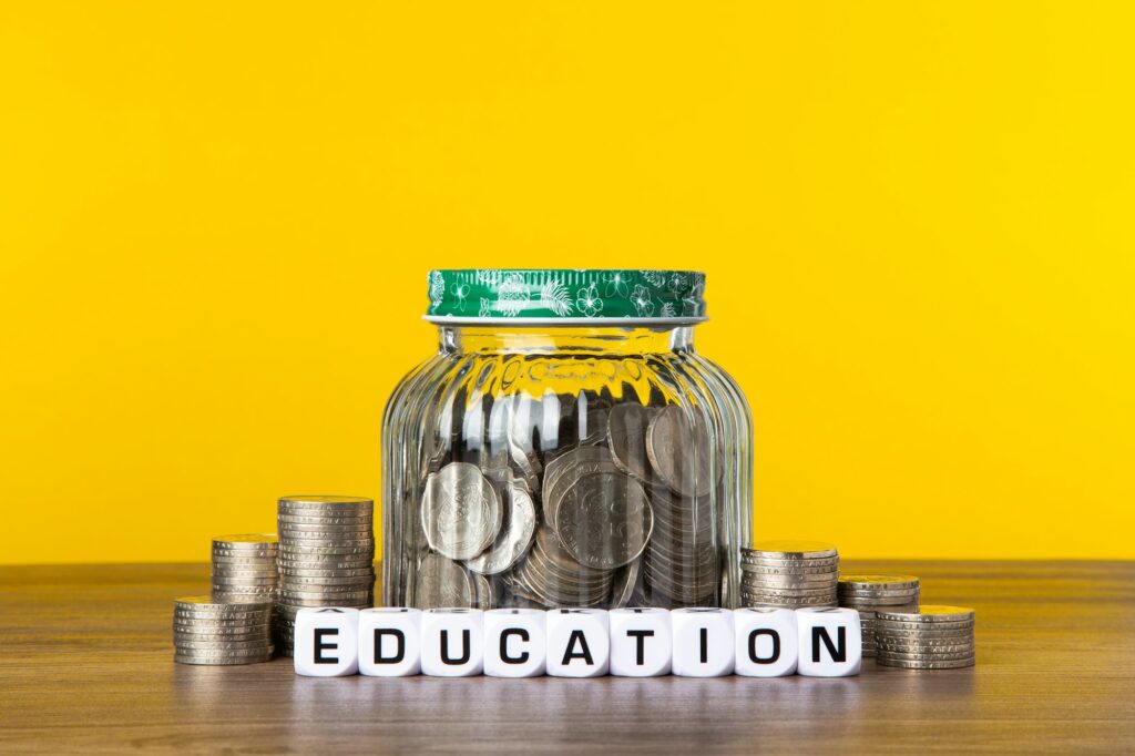 A lot coins in glass jar with yellow background. Saving for Education concept